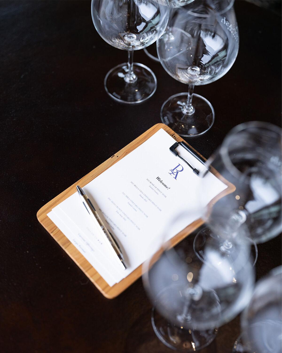 Penner-Ash tasting menu surrounded by wine glasses.